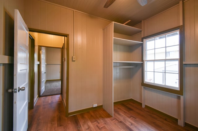 unfurnished bedroom with dark wood-type flooring and wood walls