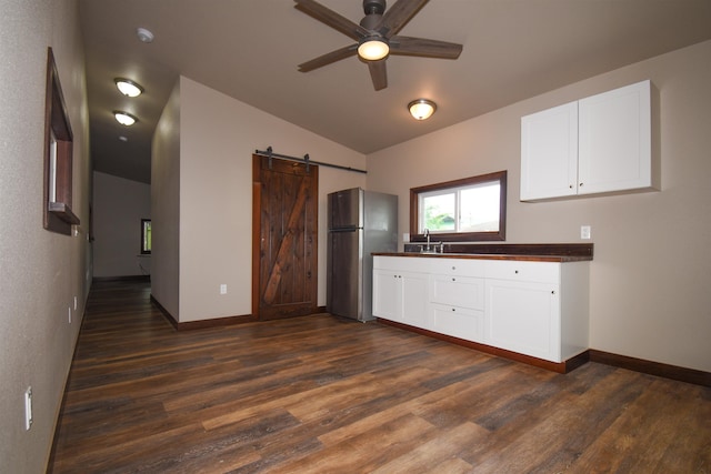 kitchen with lofted ceiling, white cabinetry, stainless steel fridge, dark hardwood / wood-style floors, and a barn door