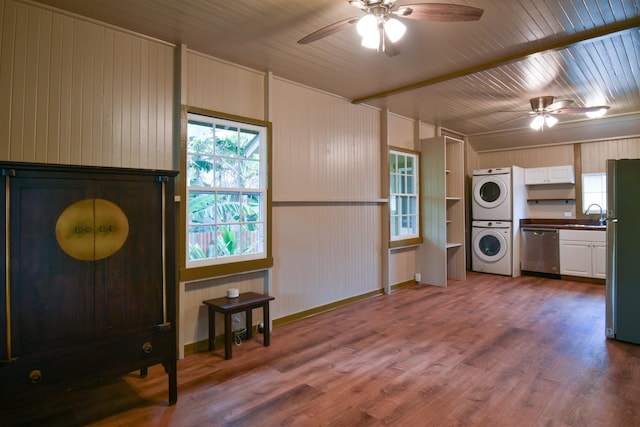 kitchen featuring stacked washer / drying machine, sink, appliances with stainless steel finishes, hardwood / wood-style flooring, and white cabinets