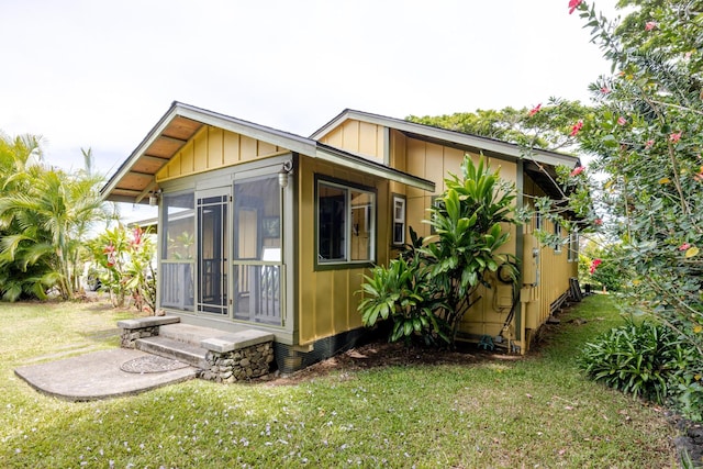 1220 W Kuiaha Rd, Haiku, HI 96708 - view of side of property featuring a sunroom, a yard, and board and batten siding