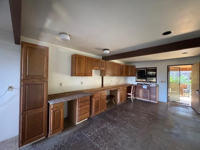 kitchen featuring beamed ceiling, concrete flooring, and brown cabinetry