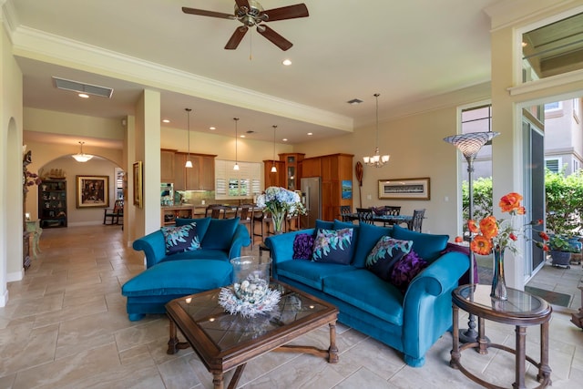 living room with plenty of natural light, ceiling fan with notable chandelier, and ornamental molding