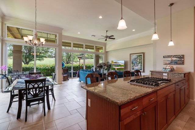 kitchen with ornamental molding, light stone counters, hanging light fixtures, and stainless steel gas cooktop