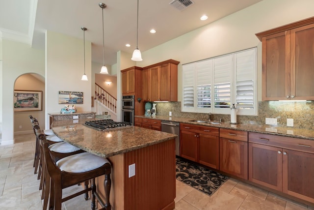 kitchen featuring dark stone countertops, hanging light fixtures, appliances with stainless steel finishes, and a kitchen island