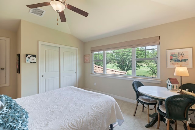 carpeted bedroom with ceiling fan, a closet, and vaulted ceiling