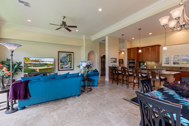 living room with ceiling fan with notable chandelier, sink, and crown molding