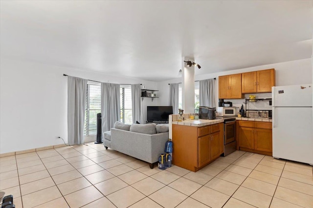 kitchen featuring light tile patterned floors, white appliances, and tile countertops