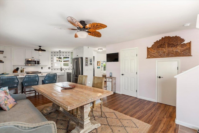 dining room with ceiling fan, sink, and dark hardwood / wood-style floors