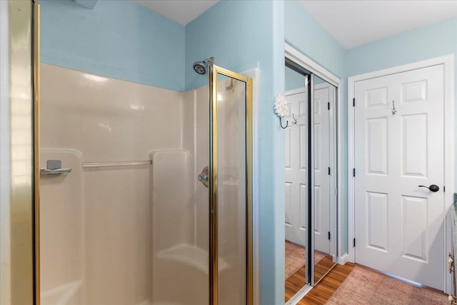 bathroom with hardwood / wood-style floors and a shower with shower door