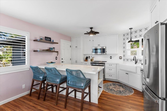 kitchen featuring kitchen peninsula, stainless steel appliances, white cabinetry, and plenty of natural light