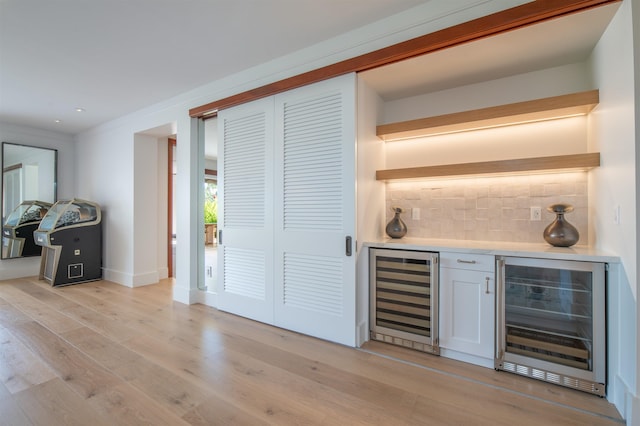 bar featuring white cabinetry, light wood-type flooring, backsplash, and wine cooler