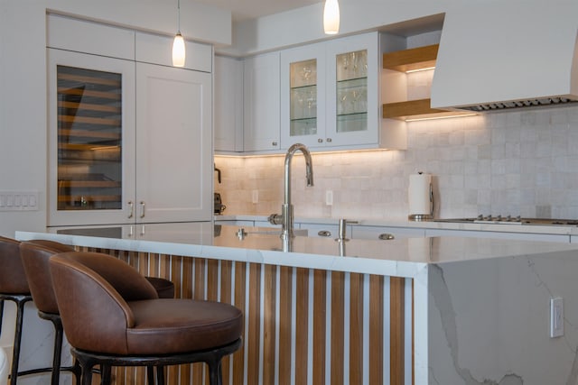 kitchen with decorative backsplash, a kitchen breakfast bar, white cabinetry, and hanging light fixtures