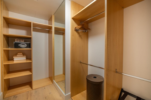 walk in closet with light hardwood / wood-style flooring