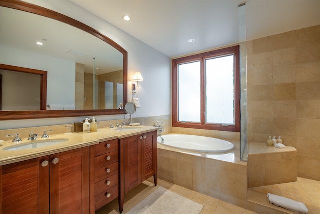 bathroom with tile patterned floors, vanity, and a relaxing tiled tub