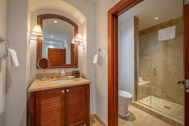 bathroom with tile patterned floors, a shower with door, vanity, and toilet