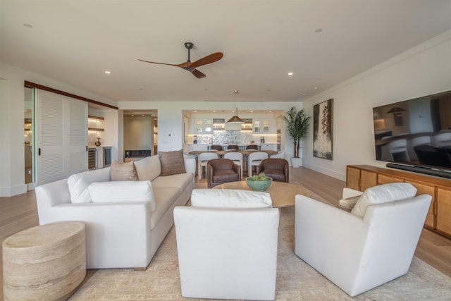 living room with light hardwood / wood-style floors, ceiling fan, and crown molding