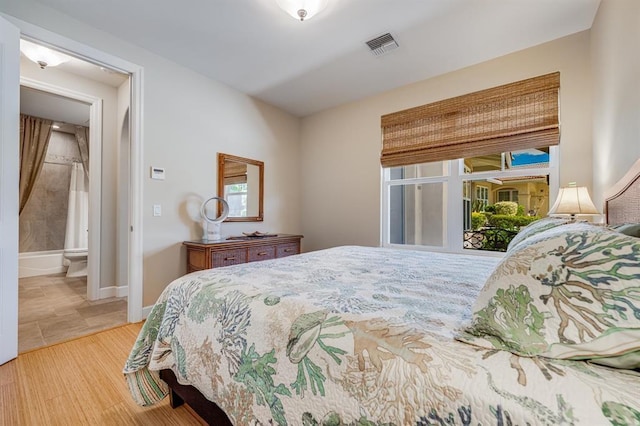 bedroom with hardwood / wood-style flooring and ensuite bathroom