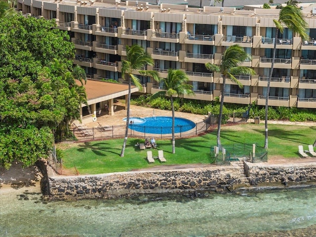 view of property's community with a yard, a pool, and a water view