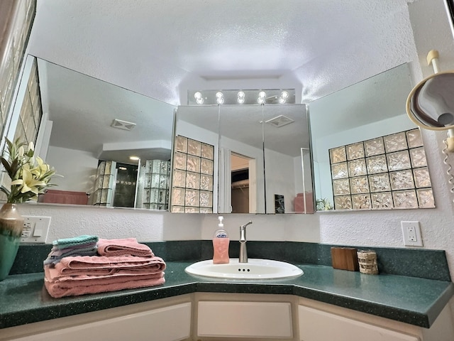 bathroom with vanity with extensive cabinet space, vaulted ceiling, and a textured ceiling