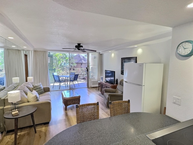 living room featuring a textured ceiling, a wall of windows, ceiling fan, and light hardwood / wood-style flooring