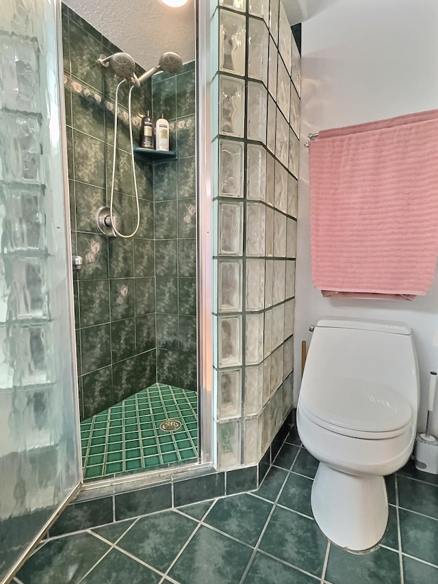 bathroom with tile flooring, tiled shower, and toilet