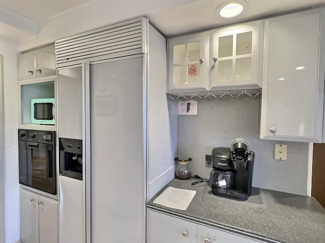 kitchen with backsplash, white cabinets, oven, and paneled fridge