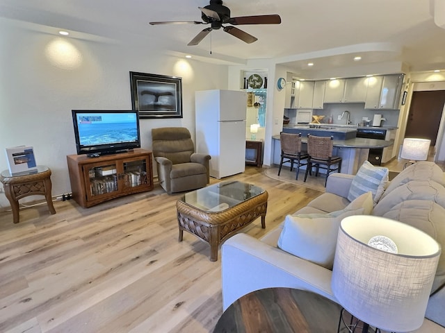 living room featuring ceiling fan, sink, and light hardwood / wood-style floors