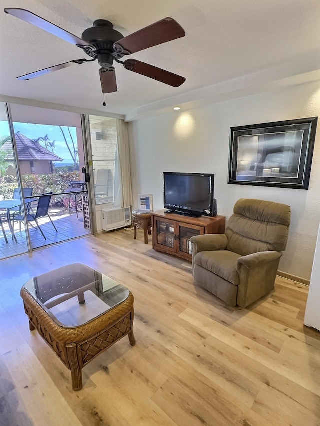 living room featuring ceiling fan, light wood-type flooring, and a wall of windows