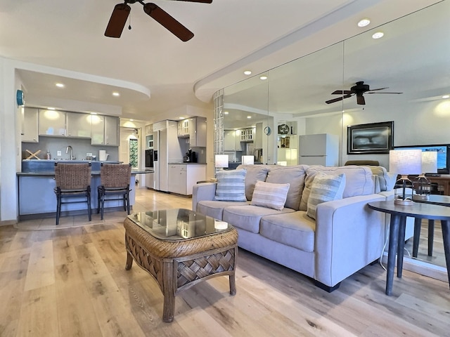 living room with ceiling fan, light wood-type flooring, and sink