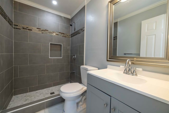 bathroom featuring toilet, vanity, tiled shower, and ornamental molding