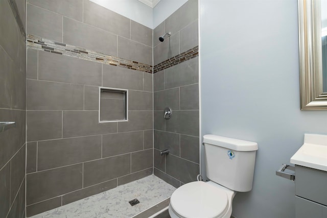 bathroom with vanity, toilet, and tiled shower