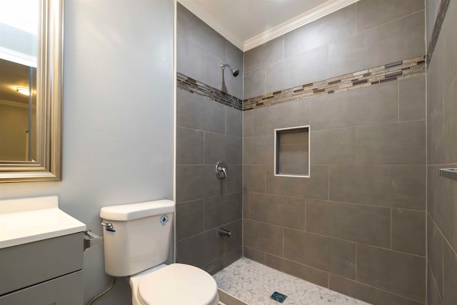 bathroom featuring vanity, toilet, tiled shower, and crown molding