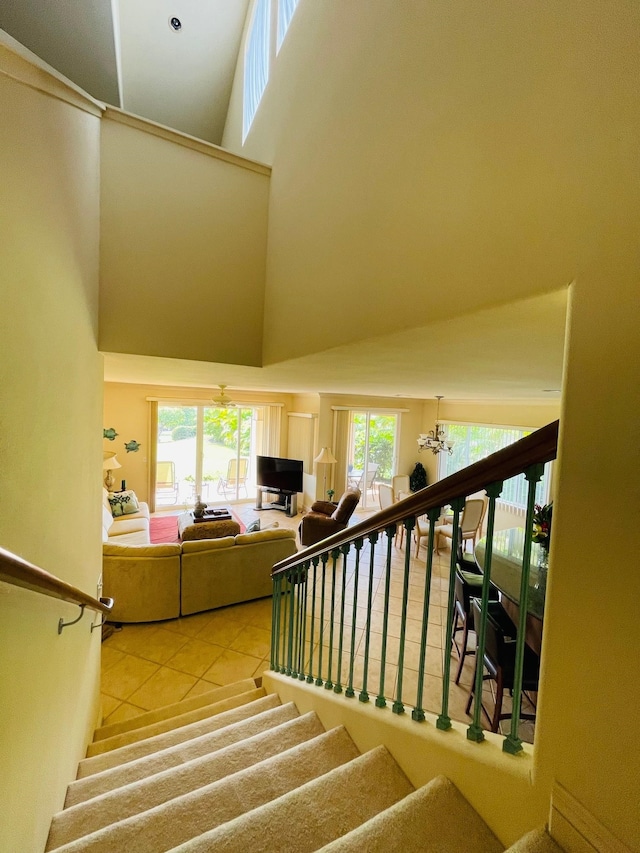 stairs with a notable chandelier, a towering ceiling, and tile patterned flooring