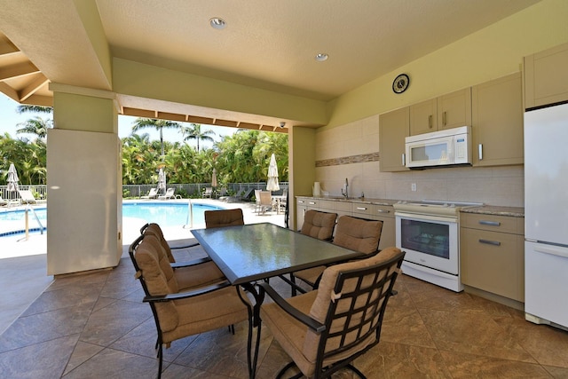 kitchen with tasteful backsplash, white appliances, light countertops, and a sink