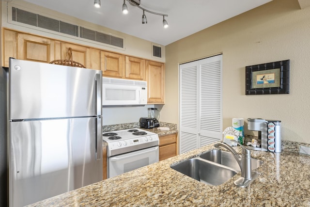 kitchen with light stone countertops, light brown cabinetry, white appliances, and sink