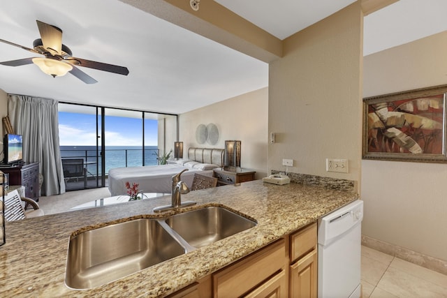 kitchen with light stone countertops, ceiling fan, sink, a water view, and dishwasher