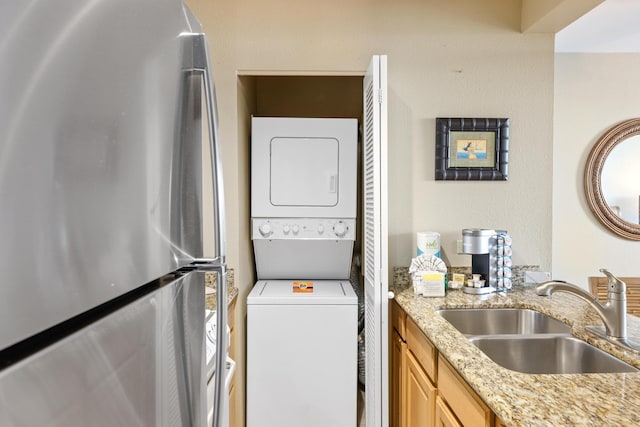 laundry area with stacked washer / dryer and sink