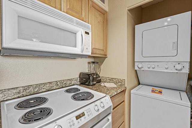 kitchen featuring light brown cabinets, stove, and stacked washer and dryer