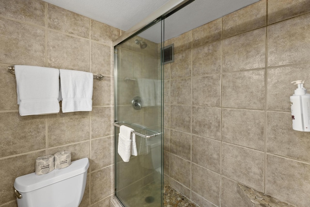 bathroom with a textured ceiling, toilet, and walk in shower