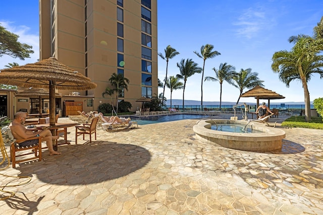 view of pool with a water view, a patio, and a hot tub