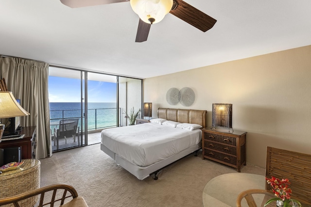 carpeted bedroom featuring access to exterior, ceiling fan, a water view, and floor to ceiling windows