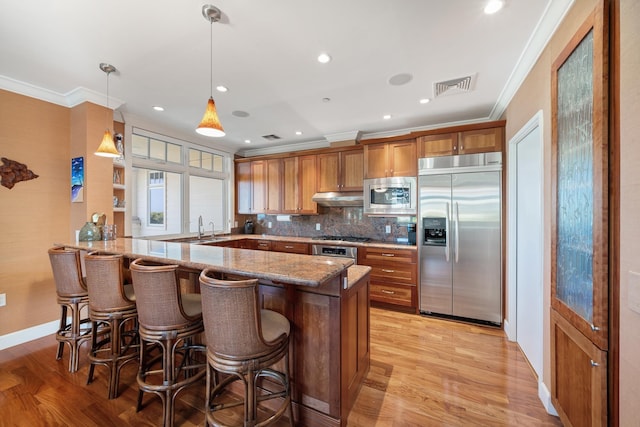 161 Wailea Ike Pl Unit D201, Kihei, HI 96753 - kitchen featuring built in appliances, brown cabinets, a peninsula, crown molding, and light wood-style floors