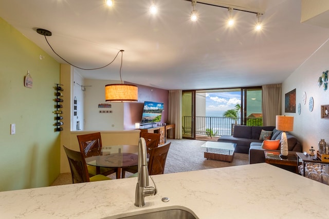 kitchen with a wall of windows, hanging light fixtures, carpet, and rail lighting