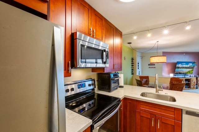 kitchen with track lighting, kitchen peninsula, sink, decorative light fixtures, and appliances with stainless steel finishes