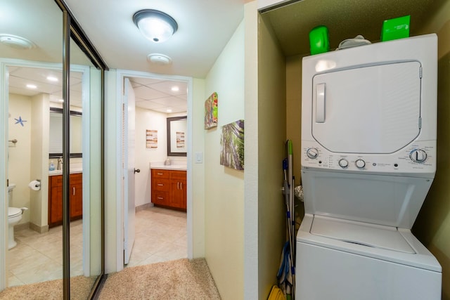 laundry room with stacked washer / dryer and light tile patterned floors