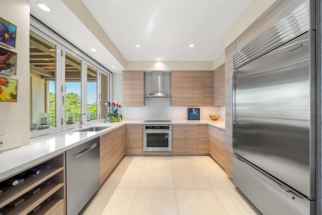 kitchen with sink, decorative backsplash, light tile patterned floors, stainless steel appliances, and wall chimney exhaust hood