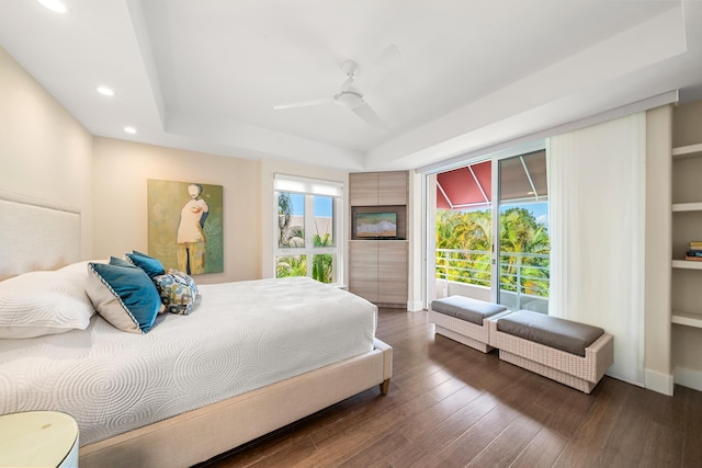 bedroom with dark wood-type flooring, a raised ceiling, and ceiling fan