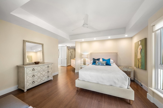 bedroom featuring dark wood-type flooring, a raised ceiling, and ceiling fan