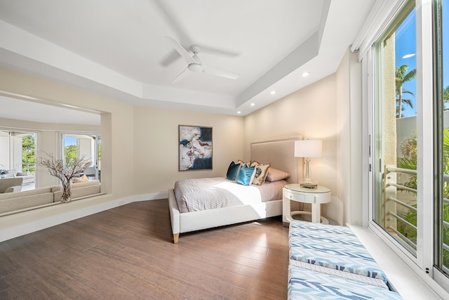 bedroom with dark hardwood / wood-style floors, ceiling fan, a tray ceiling, and access to outside