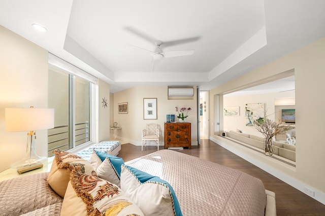 bedroom featuring dark wood-type flooring, ceiling fan, a tray ceiling, and a wall mounted AC